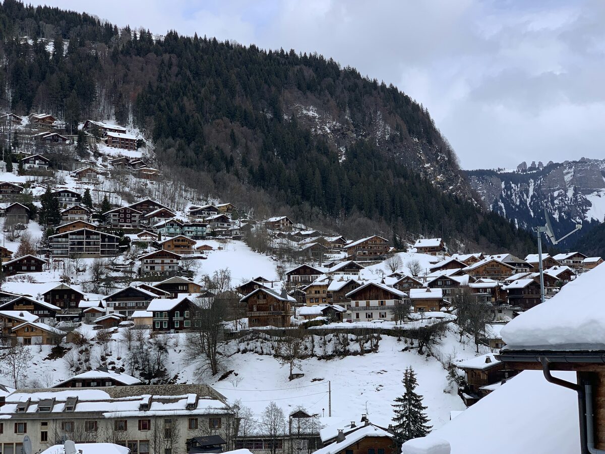 Morzine under fresh snow, chalets stacked up the hillside below a forested slope