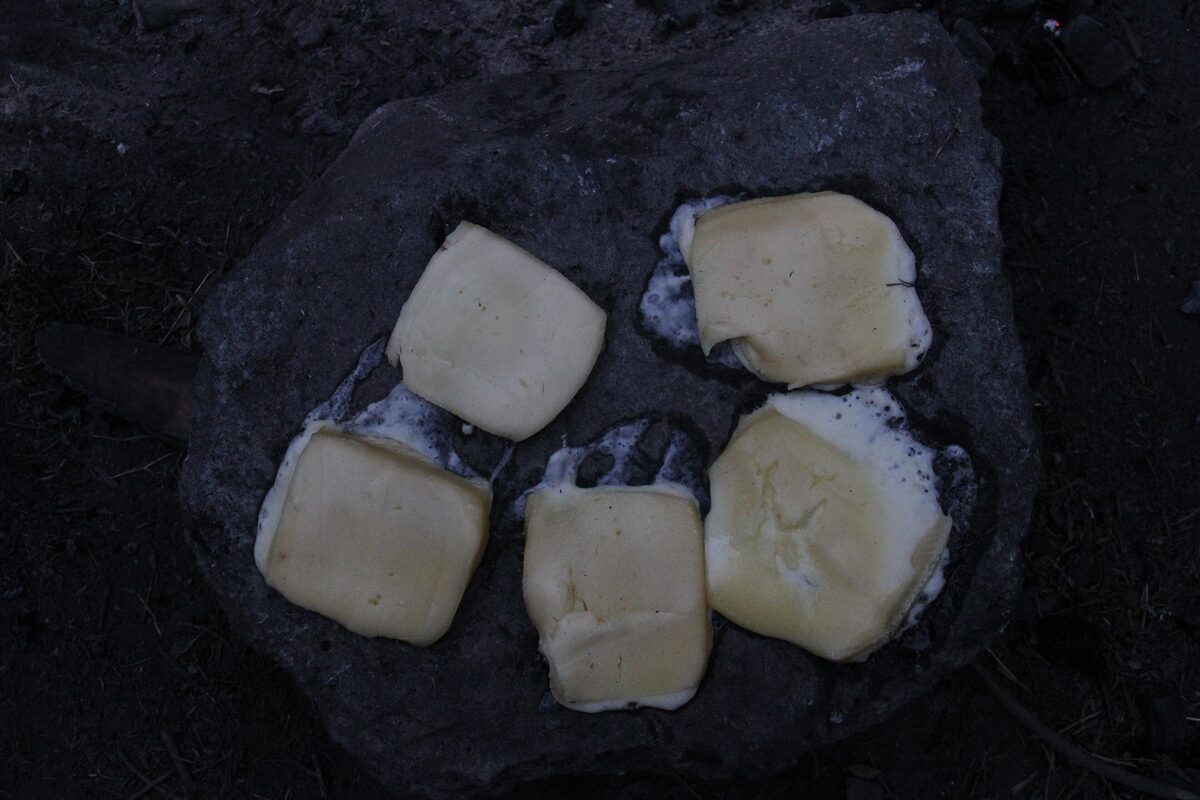 Slices of raclette cheese melting on a hot stone