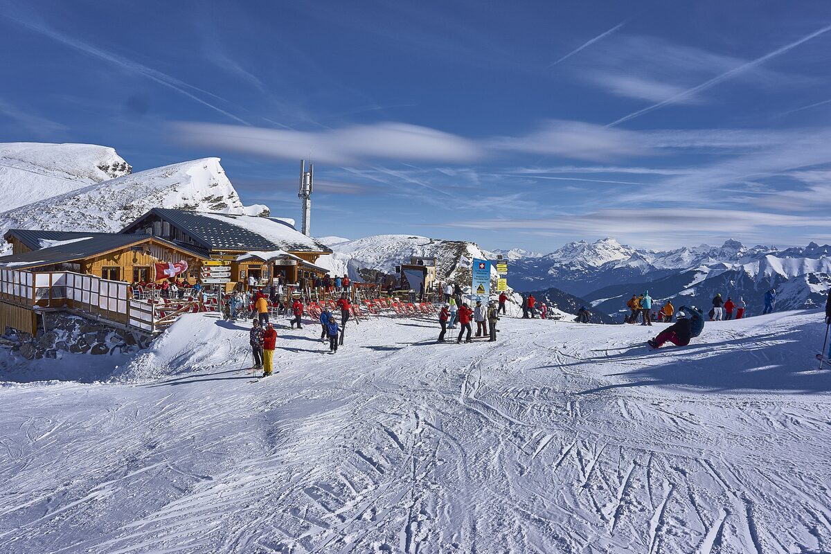 A mountain restaurant and skiers on a snowy piste at the start of the Swiss Wall