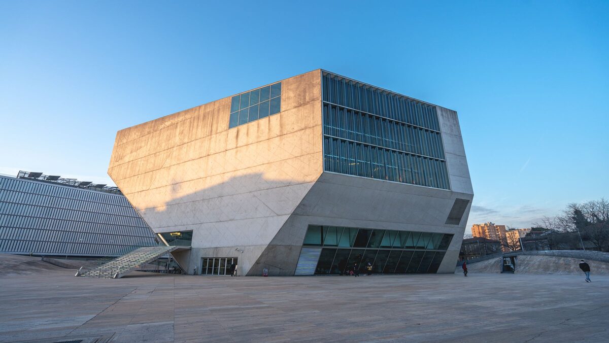 The angular concrete block of the Casa da Música concert hall in warm evening light, seen across its stone plaza