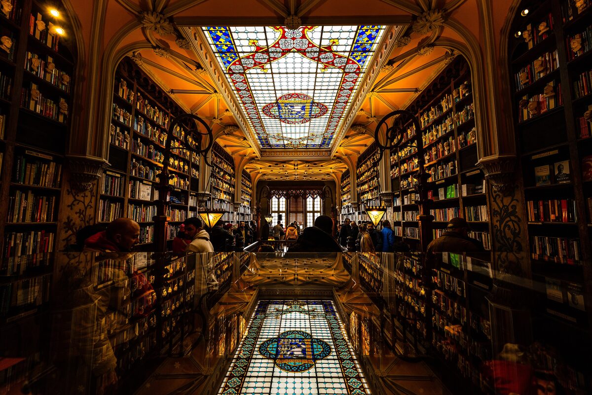 The wooden bookshelves and stained-glass skylight inside Livraria Lello