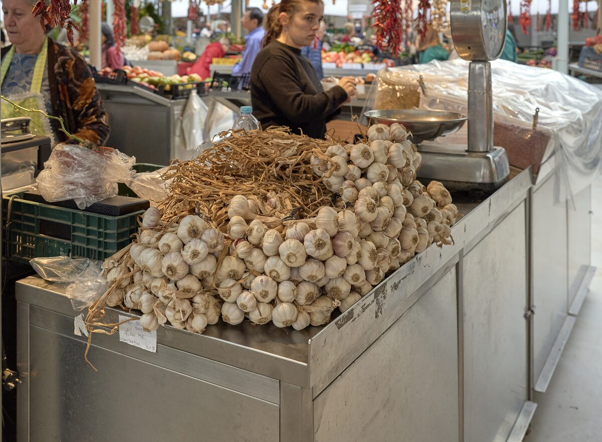 Garlic and produce on a stall inside the Mercado do Bolhão, with a vendor behind the counter