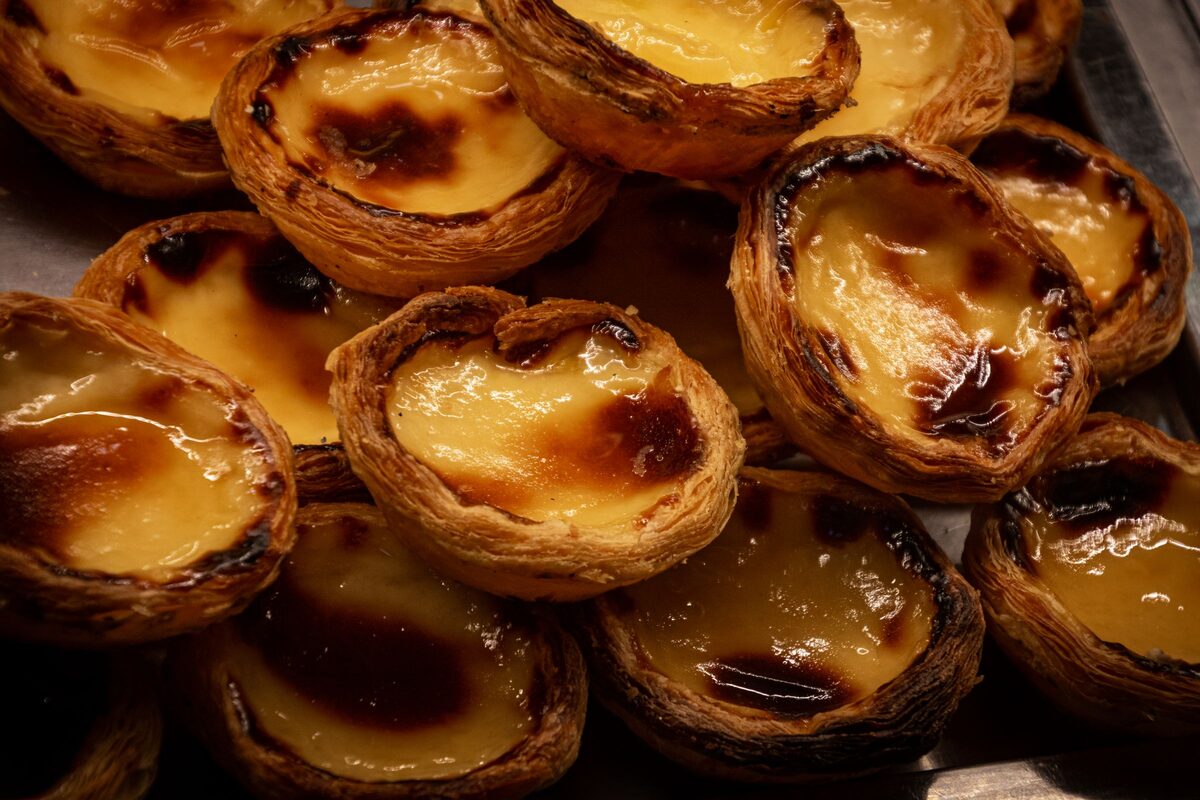 A pile of freshly baked pastéis de nata with blistered caramelized tops and golden custard