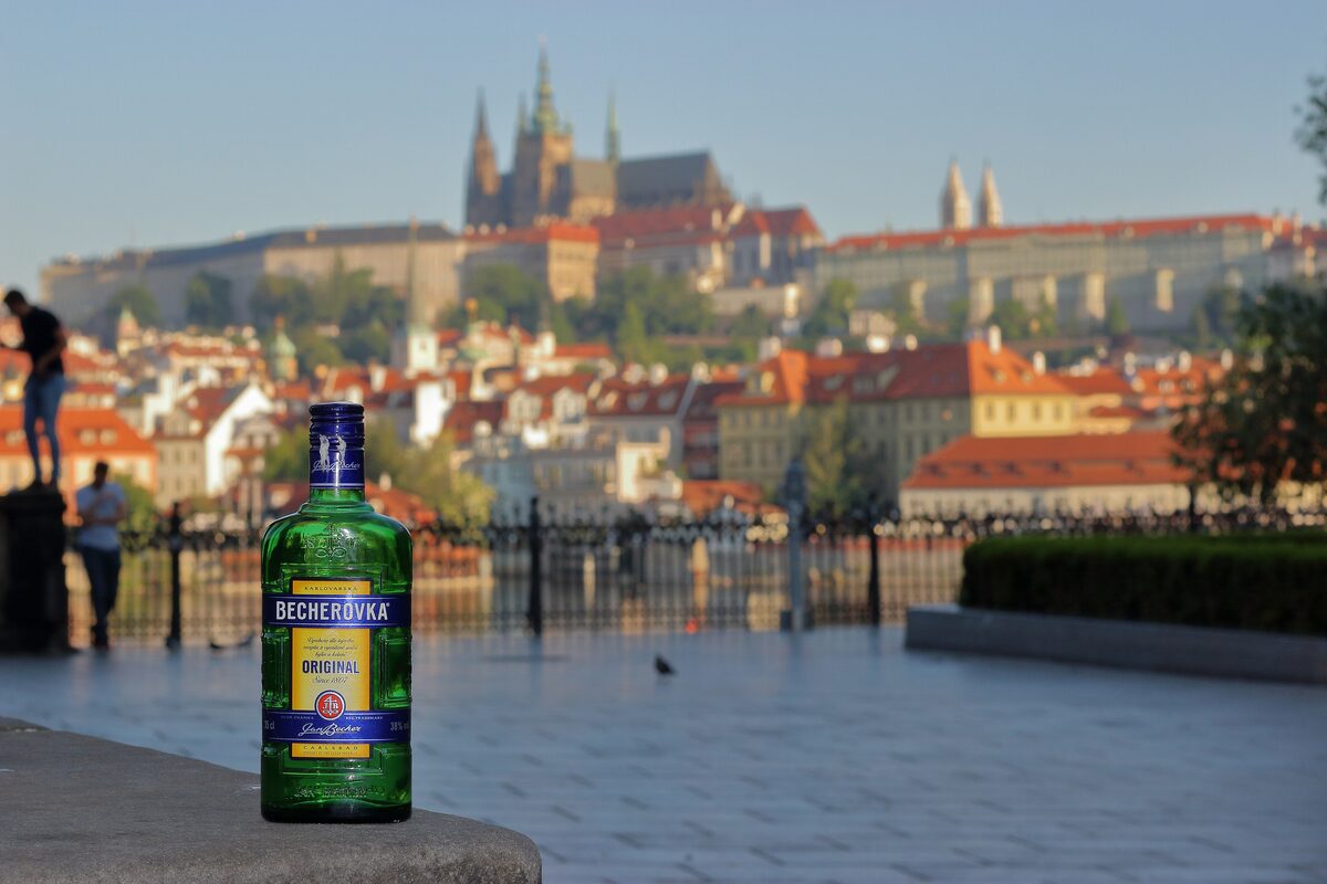 A bottle of Becherovka on a riverside wall with Prague Castle in the background