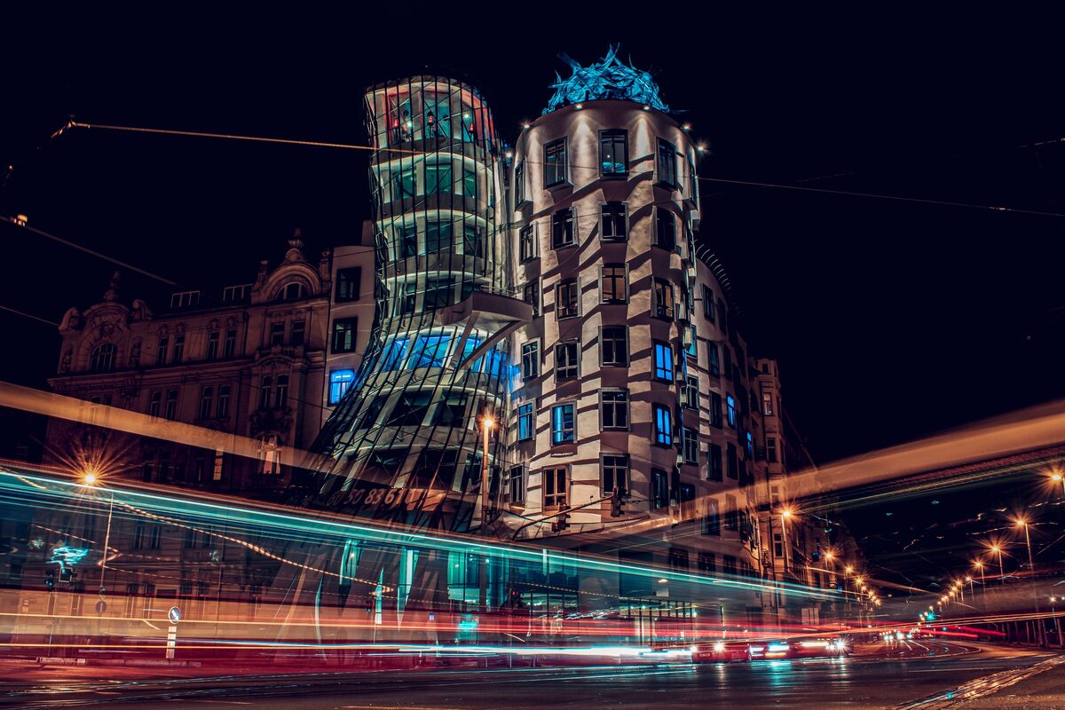 The Dancing House on the Vltava embankment at night, with light trails from traffic on the bridge road