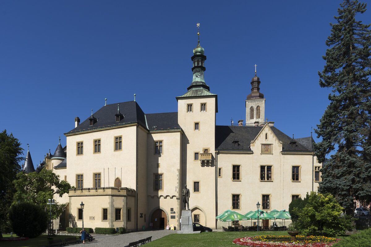 The Italian Court in Kutná Hora, a pale palace with a tall tower and green spires