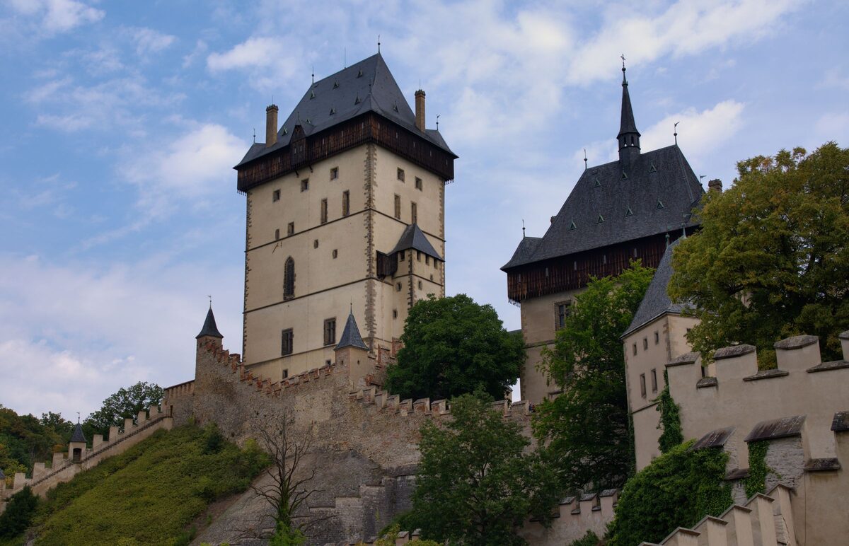 Karlštejn Castle's tall white tower and steep roofs above the wooded hill