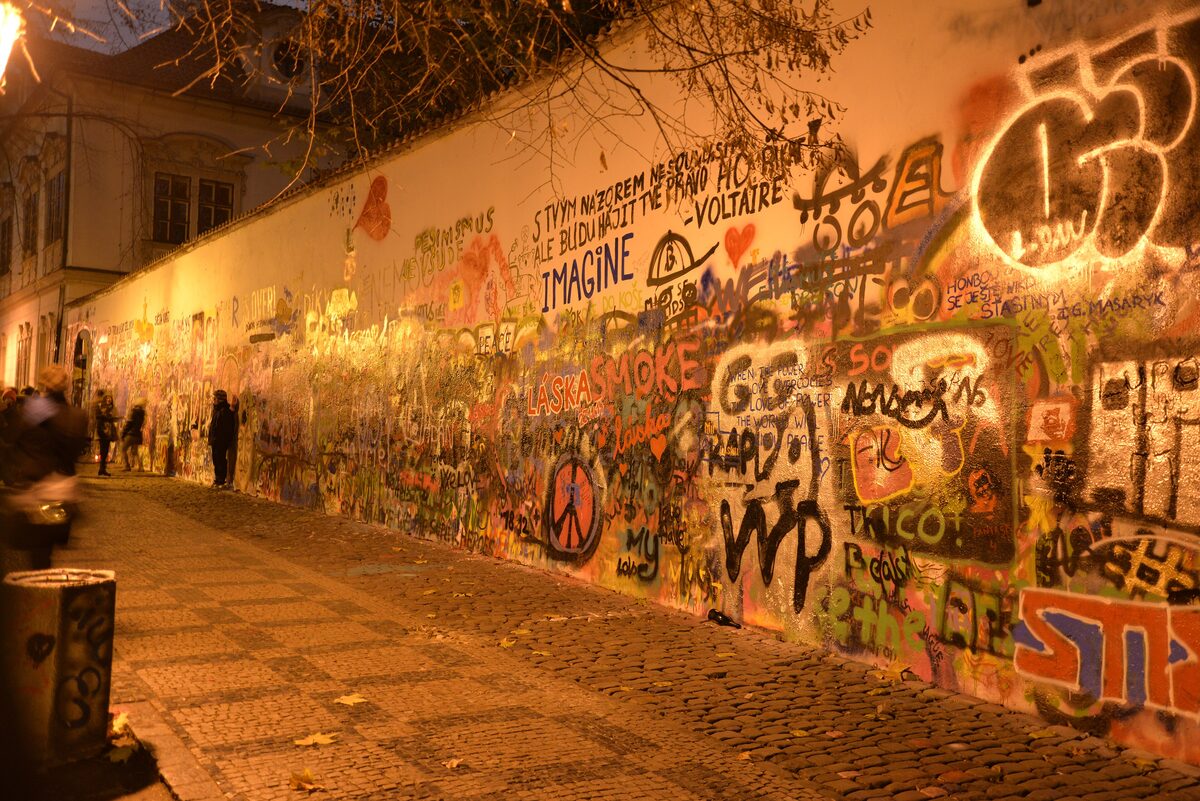 The Lennon Wall in Malá Strana, covered in layers of graffiti and painted lyrics under evening lights