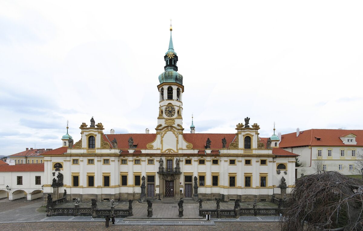 The white Baroque facade and clock tower of the Loreta on its square in Hradčany