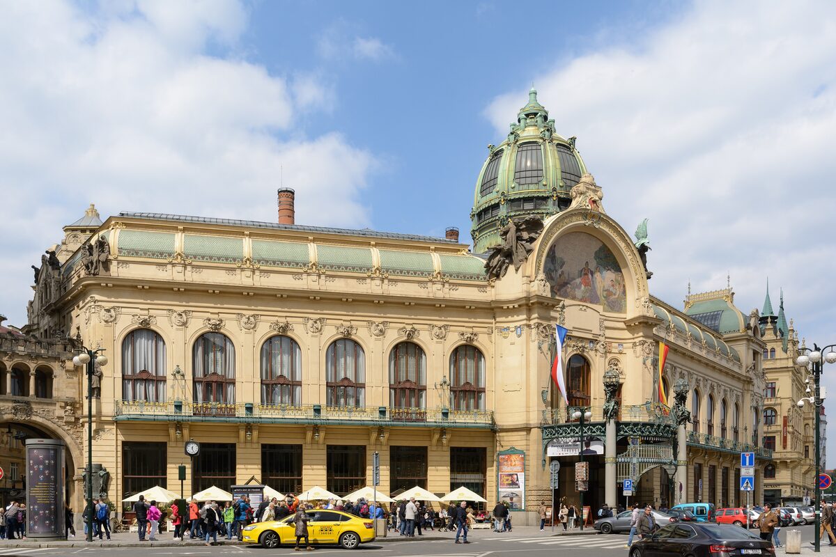 The Art Nouveau facade of the Municipal House with its green copper dome and taxis on the square