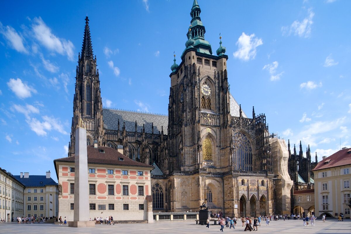 St. Vitus Cathedral's Gothic towers rising over the castle square with the obelisk in front