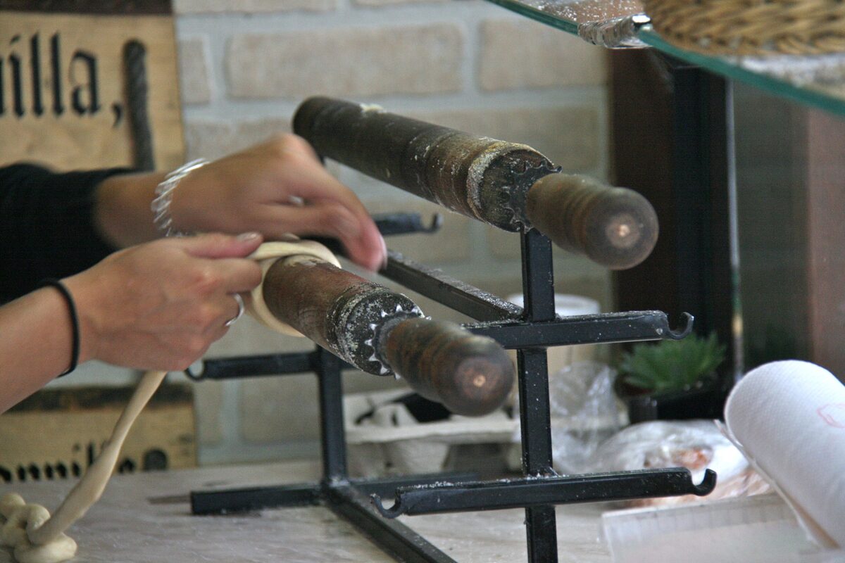 Dough being wound around a metal roller for trdelník, the rolled pastry sold on Prague's streets