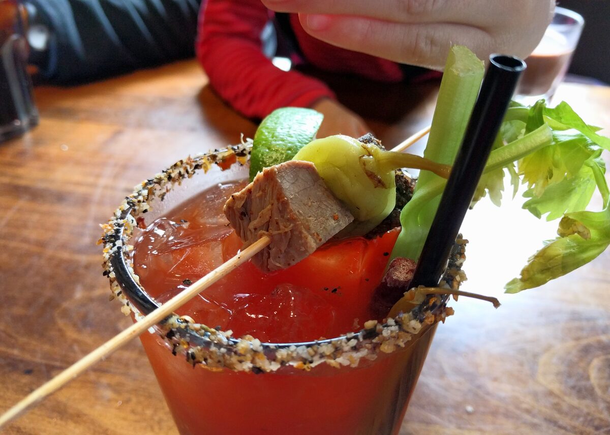 A Caesar cocktail with pickled pepper, celery and lime garnish