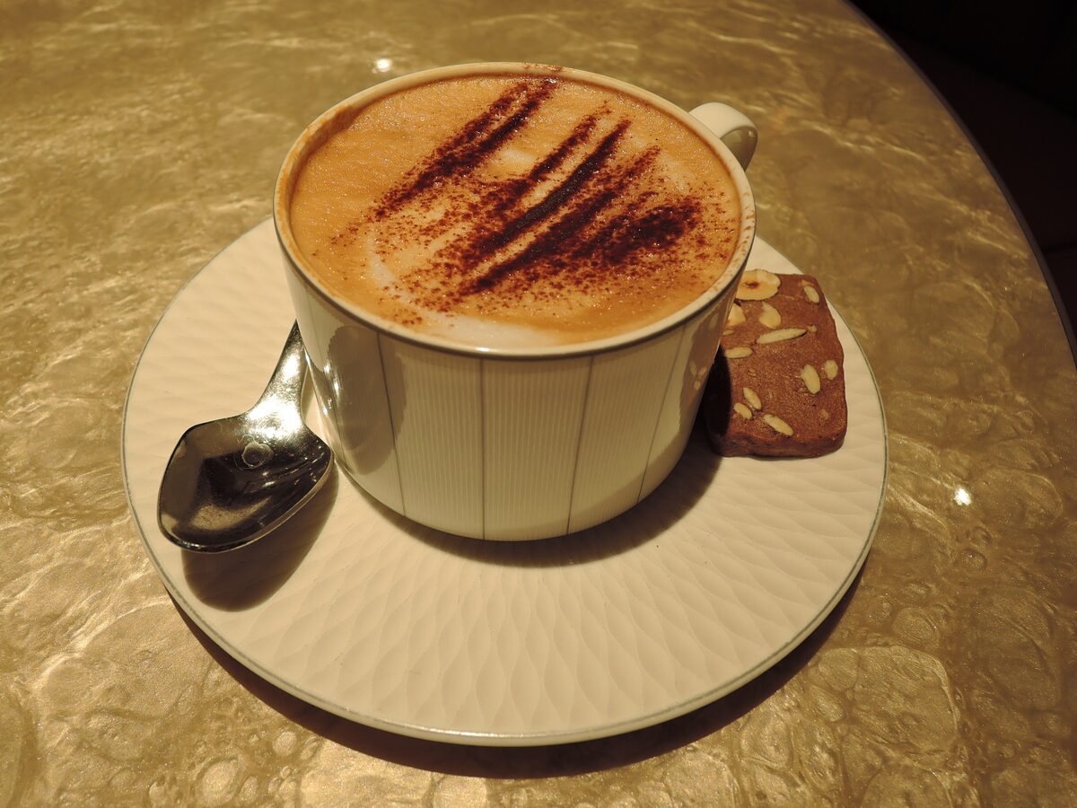 Cappuccino with cocoa pattern and a biscuit on the saucer