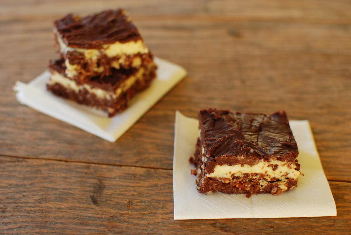 Two Nanaimo bars on napkins showing chocolate and custard layers