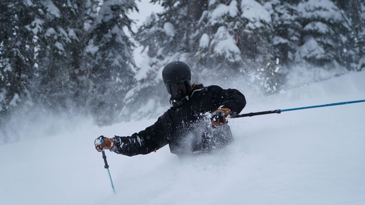 Skier in deep powder with poles raised through the spray