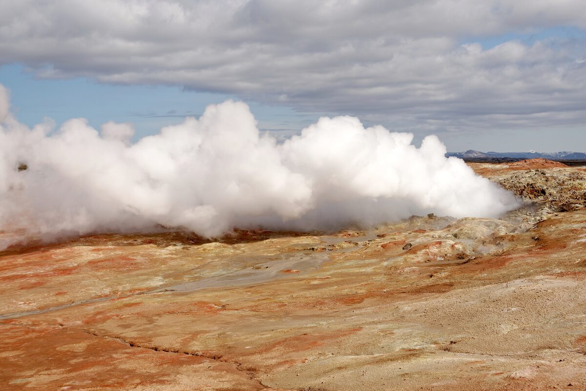 Steam rising from a vent on the orange and red ground of the Gunnuhver geothermal area