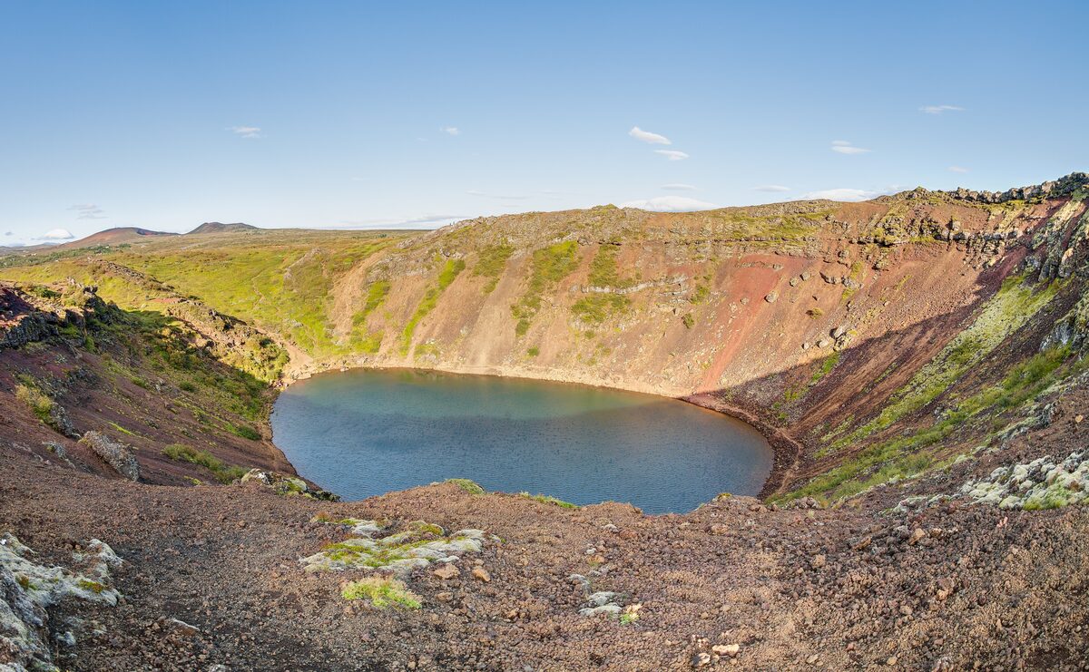 Kerið crater with its blue lake inside red and green volcanic slopes