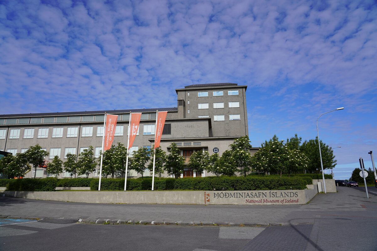 The National Museum of Iceland building on a sunny day, with flags and the museum name on the wall