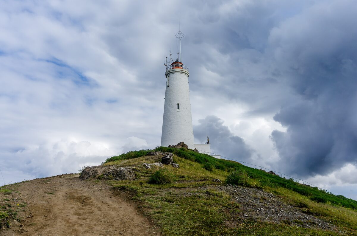 Reykjanesviti lighthouse on a grassy hill under a cloudy sky