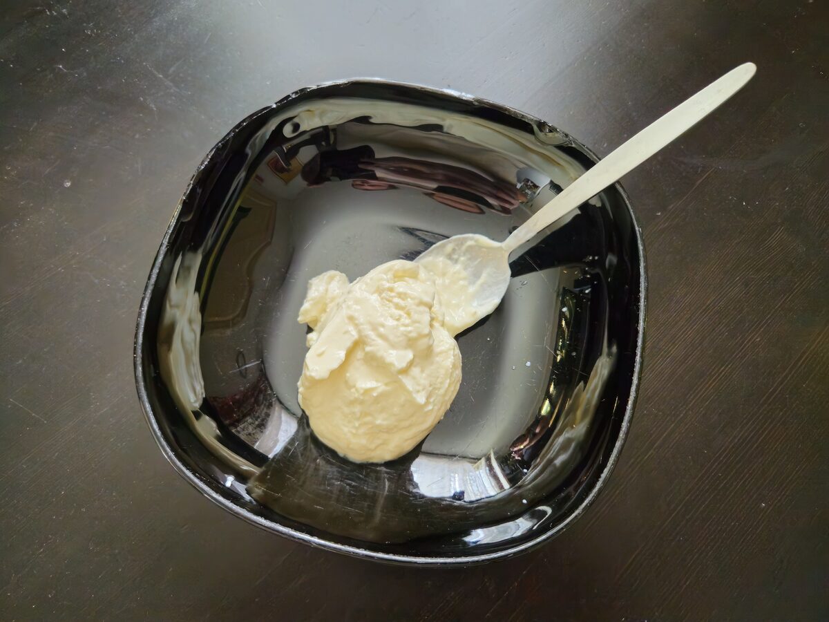 A scoop of thick skyr with a spoon in a glossy black bowl