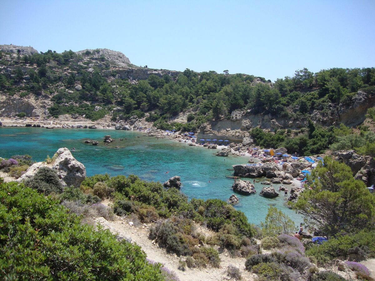 Anthony Quinn Bay, a rocky cove of turquoise water backed by pine-covered cliffs