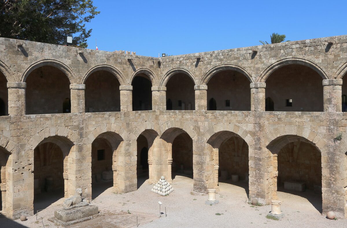 The arcaded two-storey courtyard of the Hospital of the Knights, now the Archaeological Museum, with a pyramid of cannonballs on the ground