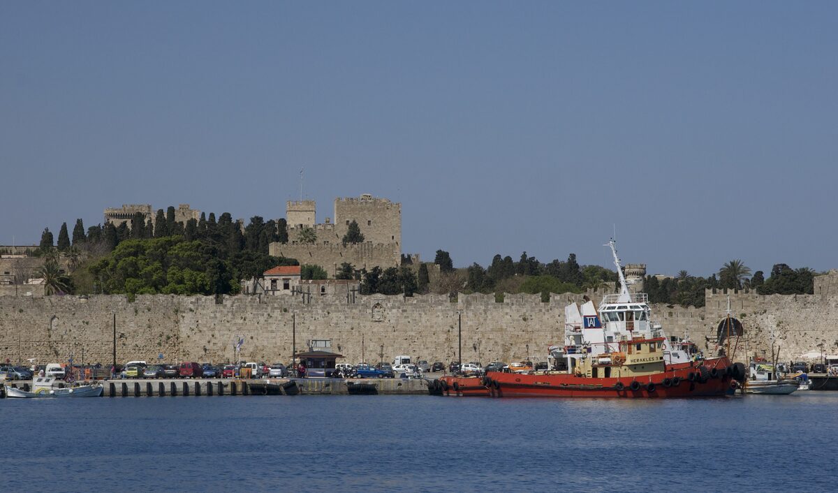 The Old Town walls rising above the harbor, with a red tugboat moored in front of them