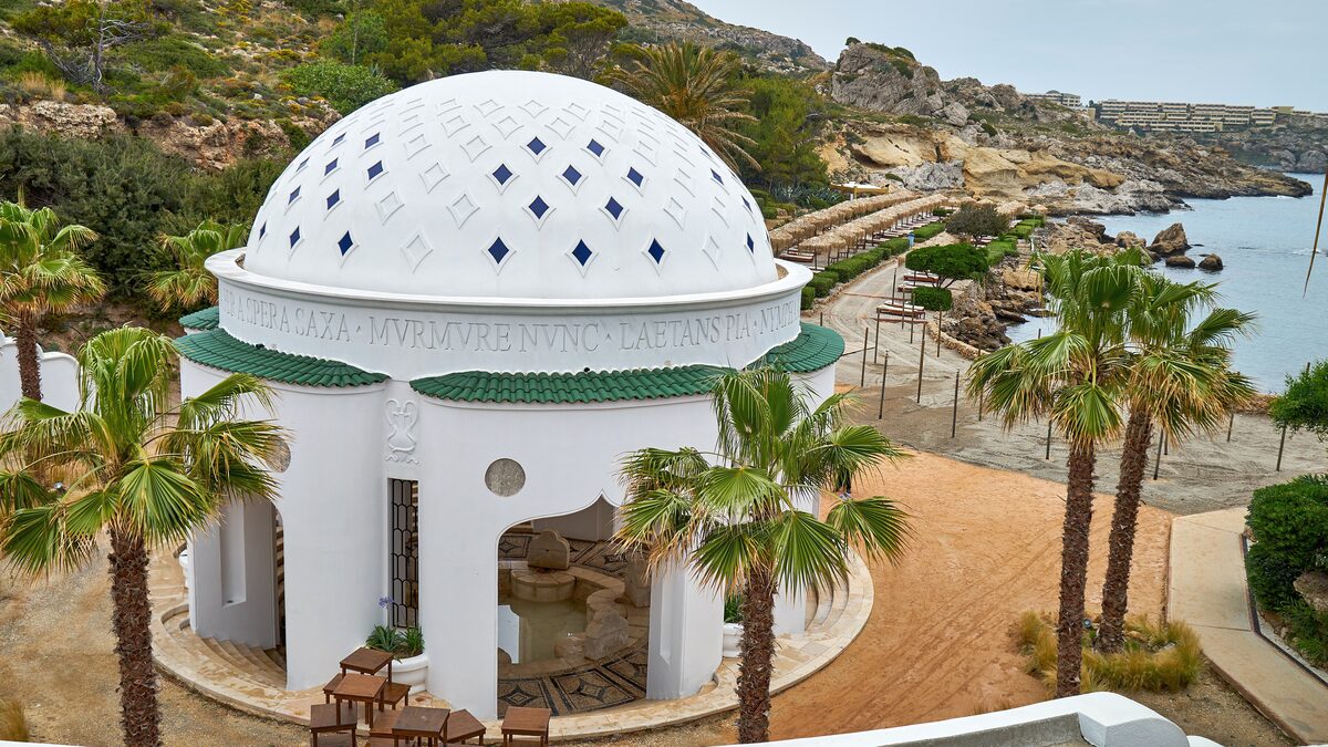 The white domed rotunda of Kallithea Springs above the rocky bay, framed by palm trees