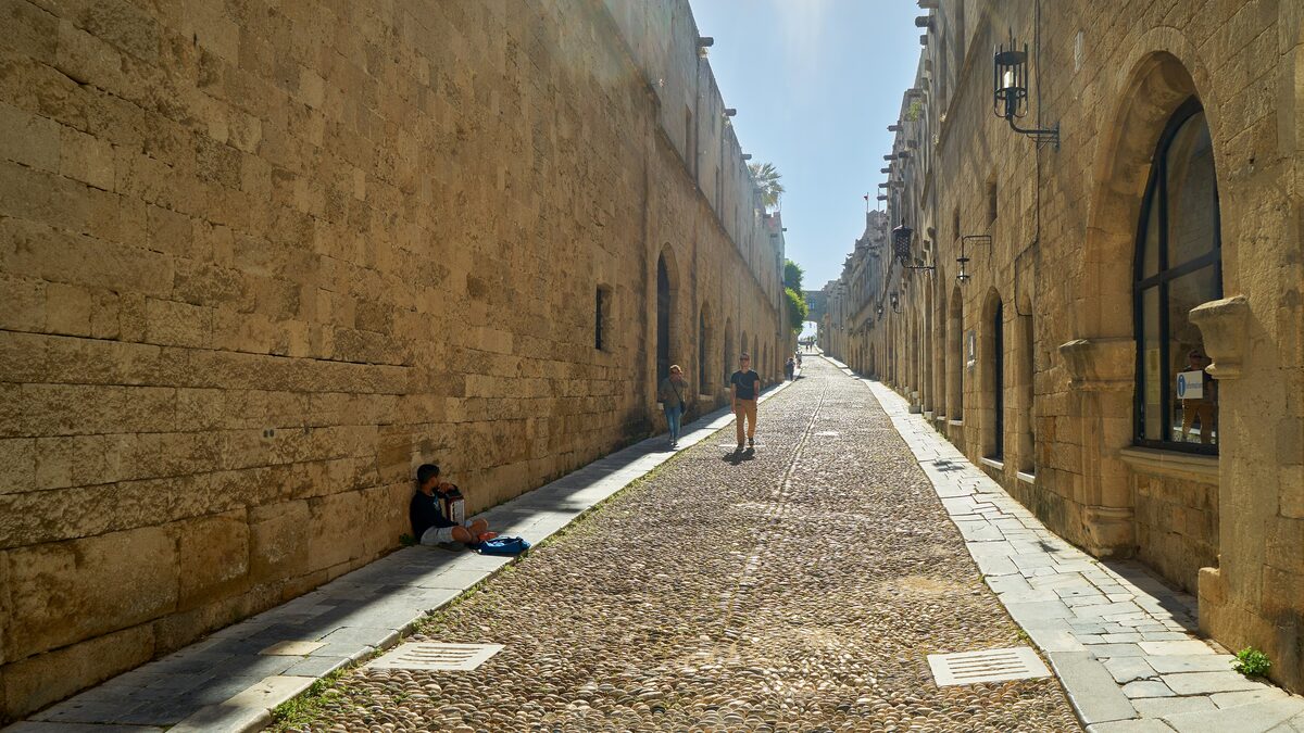 The cobbled Street of the Knights running straight between restored stone walls and arched doorways