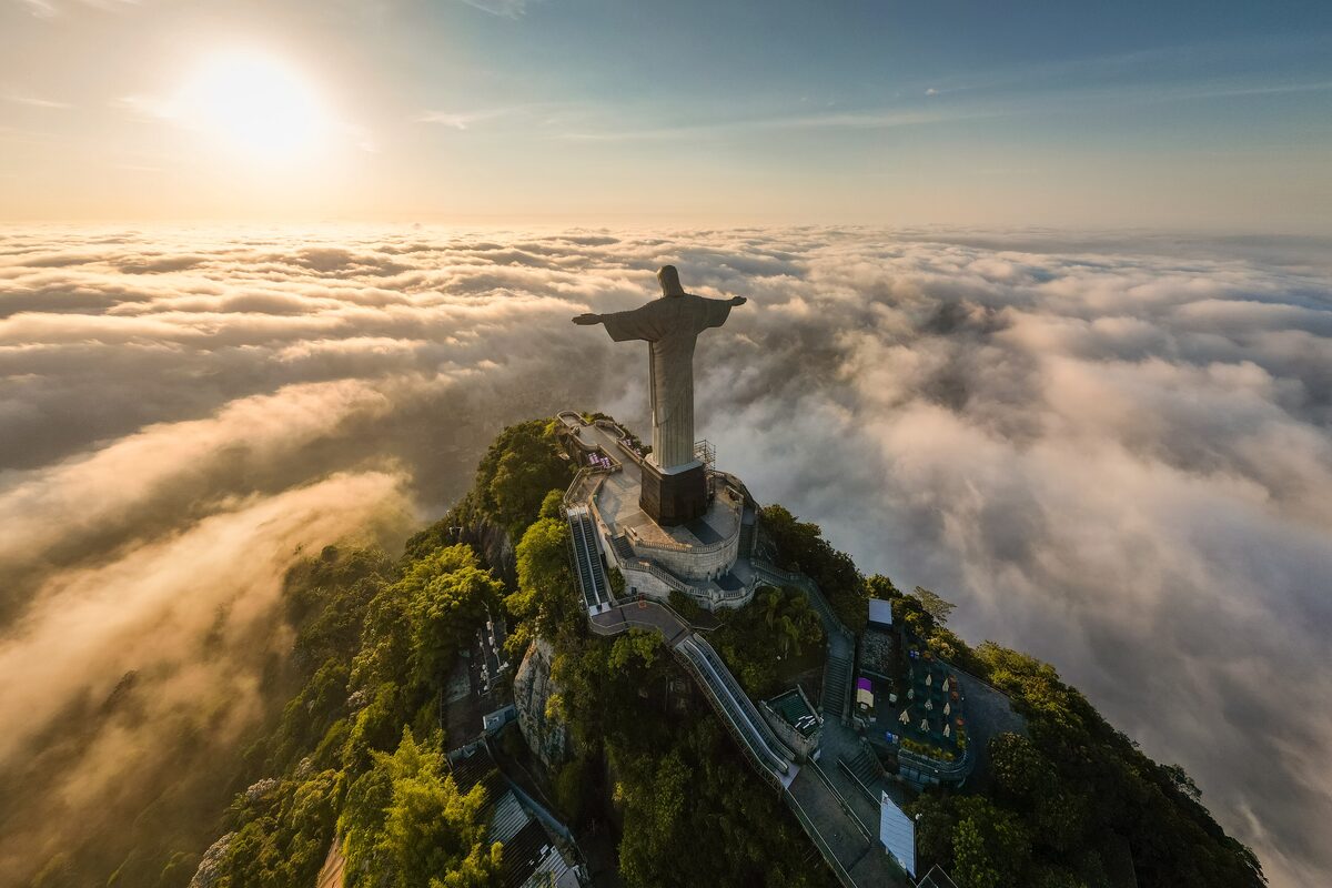The Christ the Redeemer statue standing above a sea of clouds at sunrise