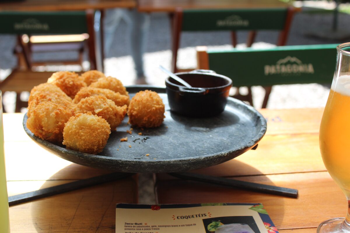 Mini coxinha croquettes, golden and crumbed, on a dark plate at a table