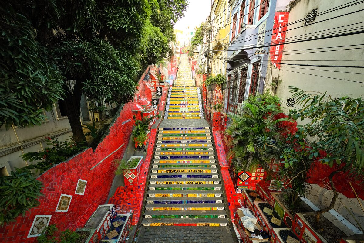 The Escadaria Selarón steps covered in blue, yellow and green tiles, with red walls on either side