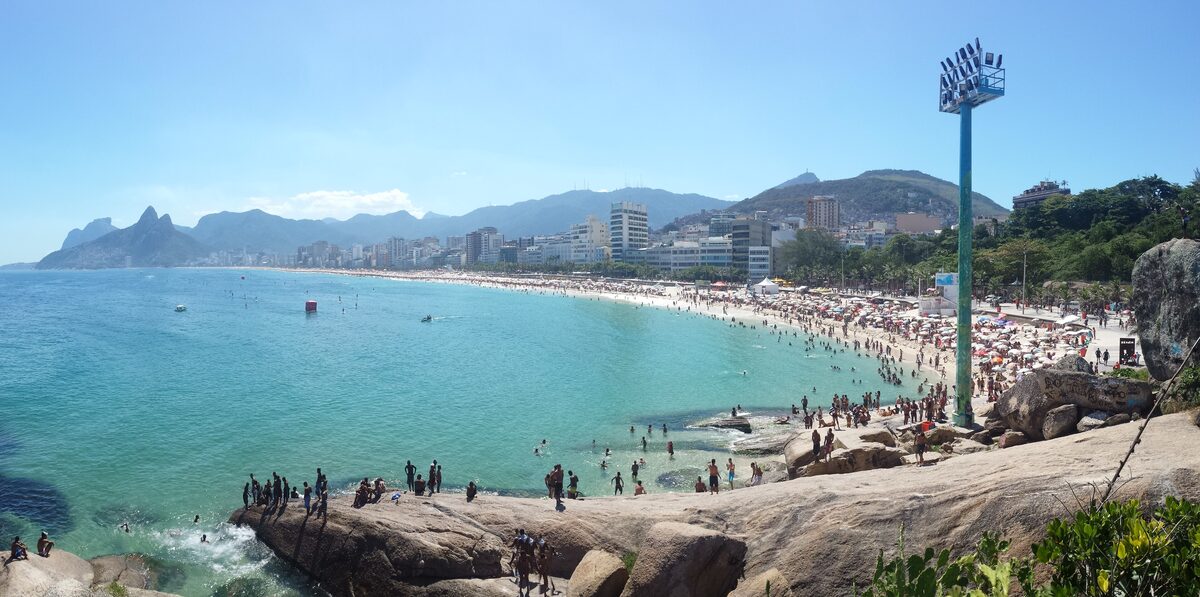 Ipanema beach in sunshine with people on the sand and turquoise water, seen from the Arpoador rocks