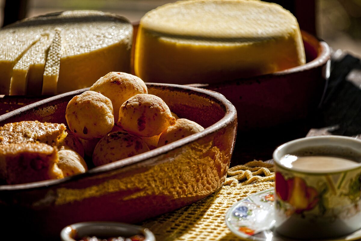 Pão de queijo cheese bread balls in a clay bowl next to a block of cheese