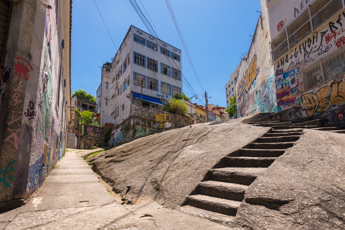 The steps cut into the granite of Pedra do Sal, between a graffiti-covered wall and an apartment block, under a blue sky