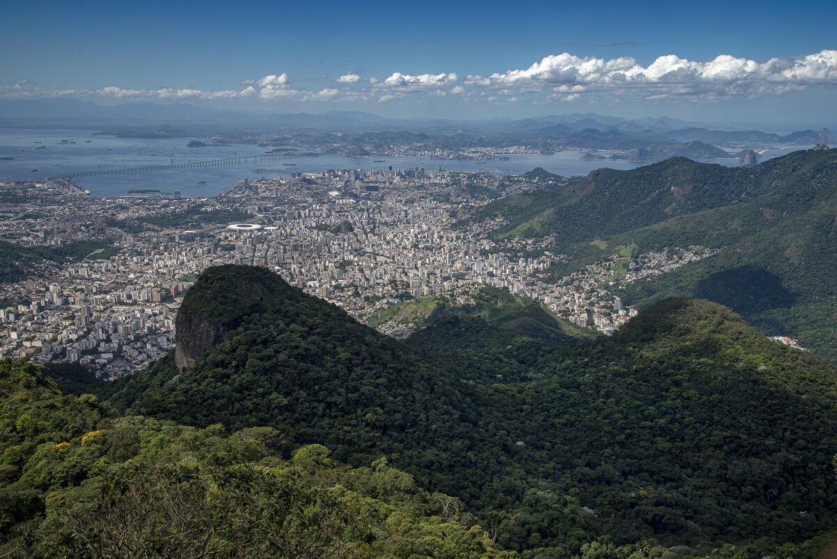 View from the Tijuca peak over forested ridges toward the city and the bay under scattered clouds
