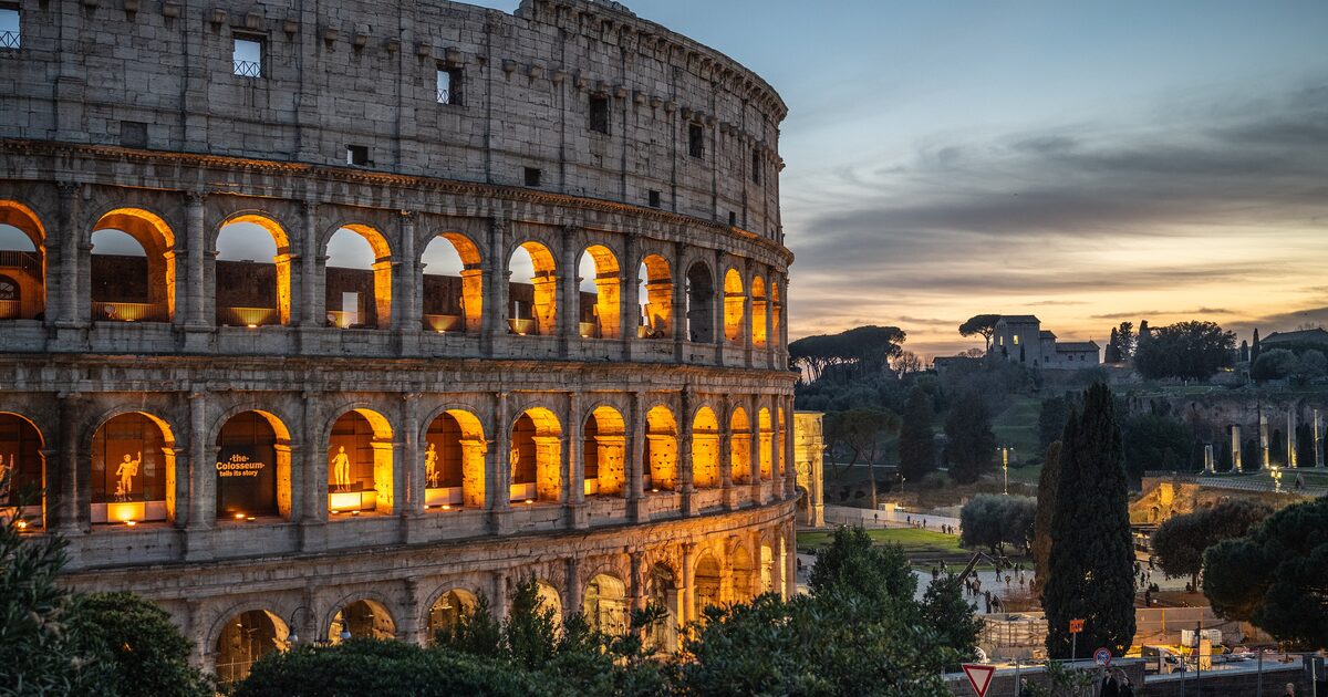 The Colosseum glowing at dusk above the Roman Forum