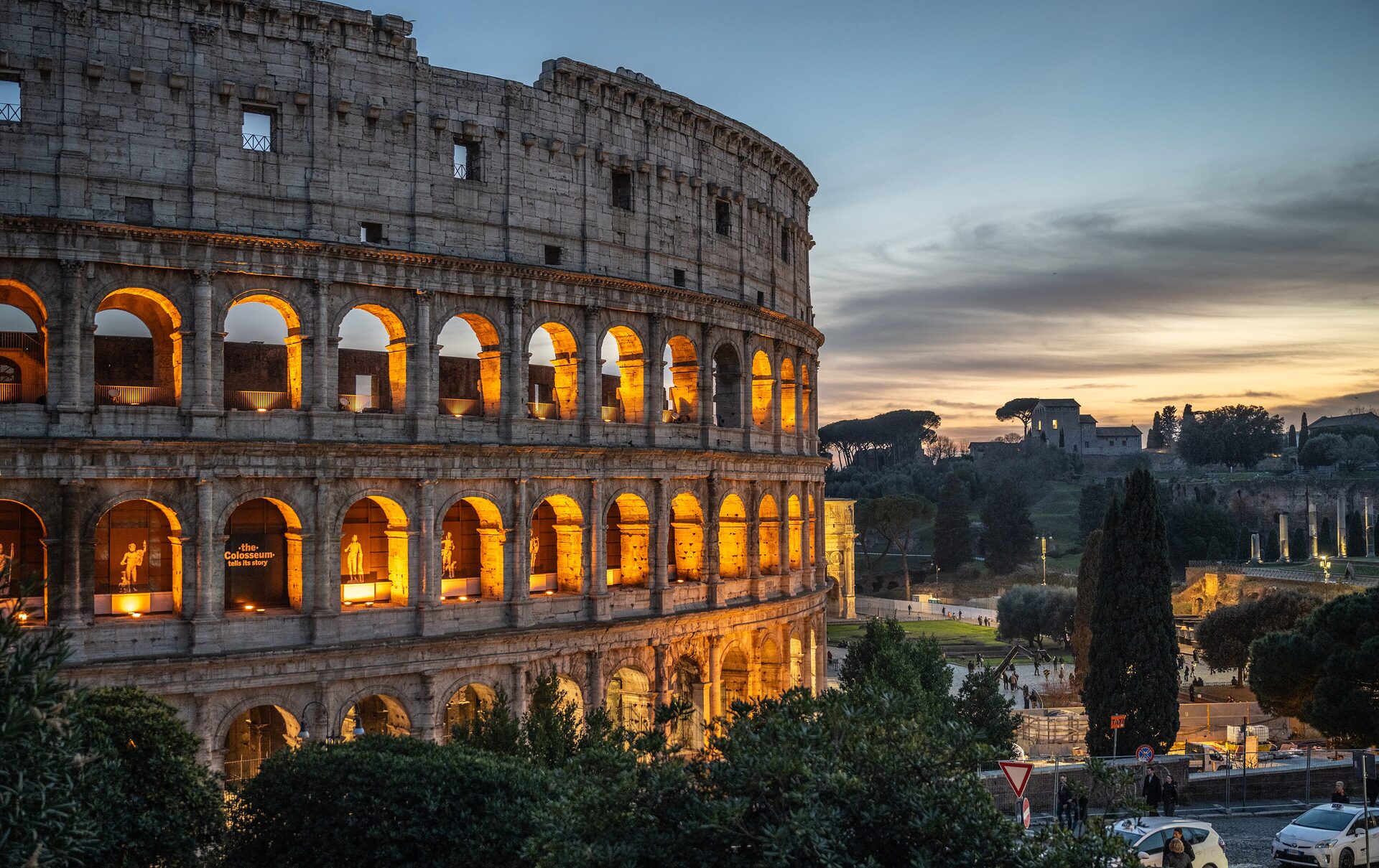 The Colosseum glowing at dusk above the Roman Forum