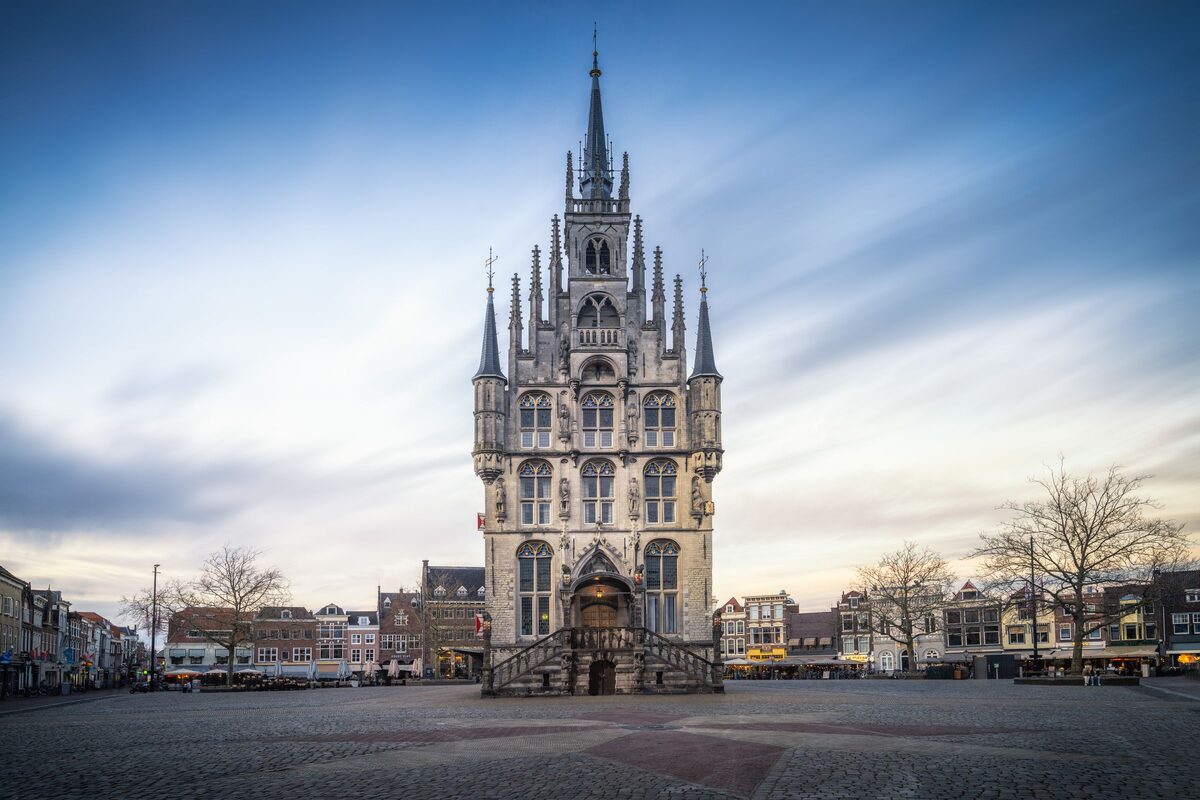 The white Gothic town hall of Gouda with its red shutters and pinnacles, standing alone on the wide market square