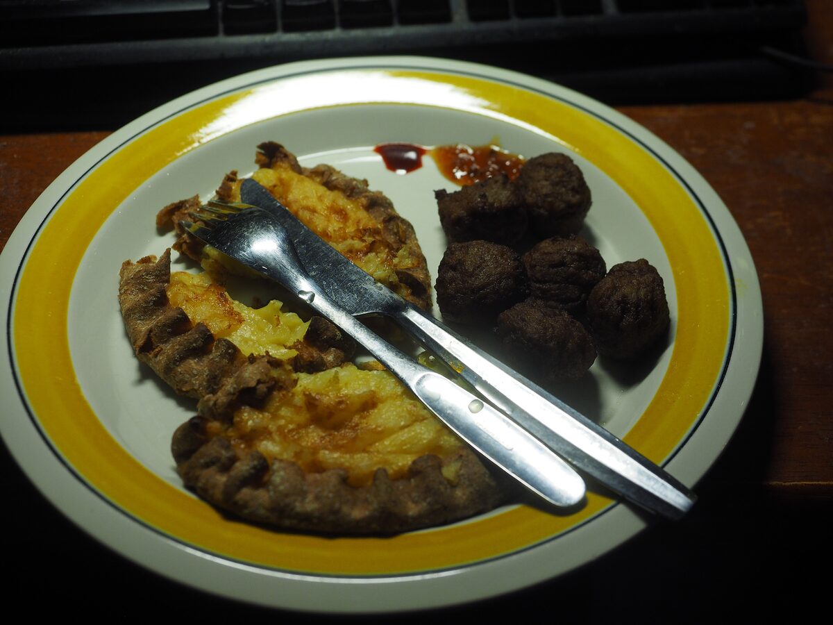 Karelian pies with rye crusts and rice filling next to meatballs on a plate