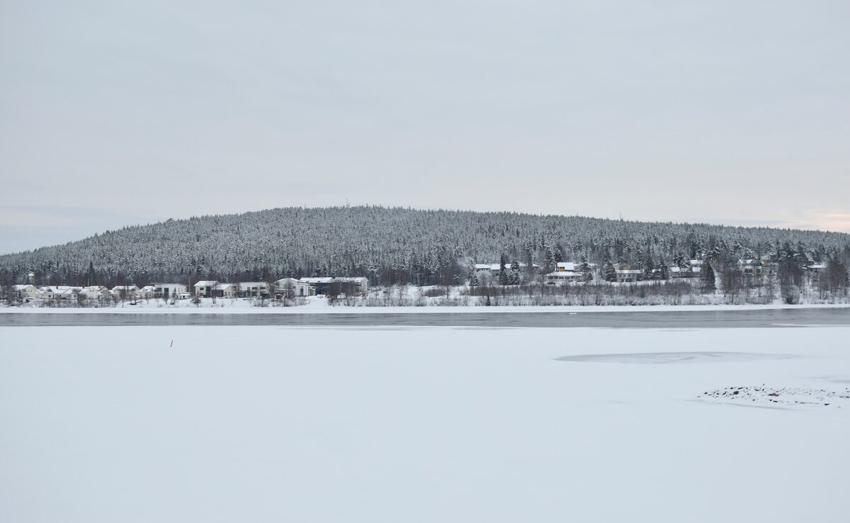 The low forested fell of Ounasvaara rising beyond the wide, frozen and snow-covered river