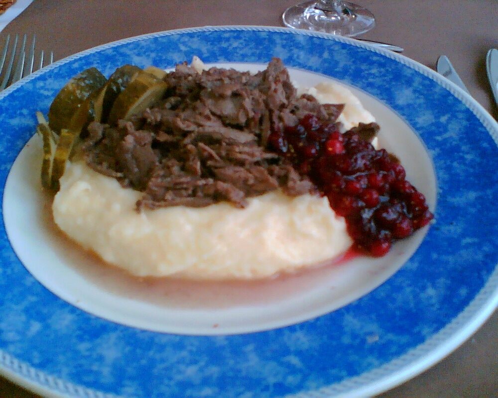 A plate of sautéed reindeer with mashed potatoes, lingonberries and pickled cucumber