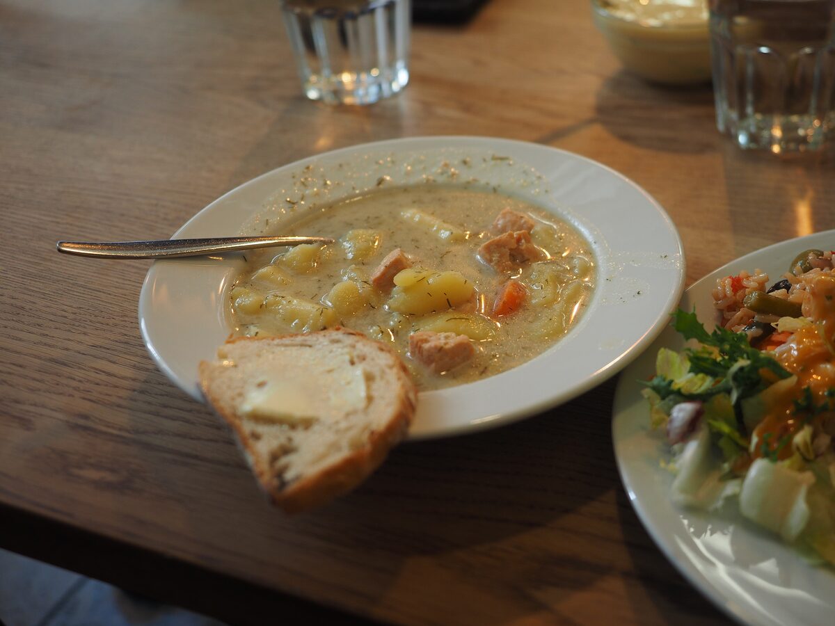 A bowl of creamy salmon soup with potatoes and carrots, with bread on the side