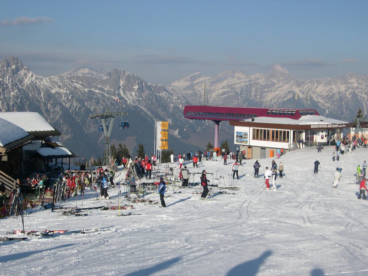 The mountain station of the Asitzbahn in Leogang on a winter day, with skiers and the ridges behind
