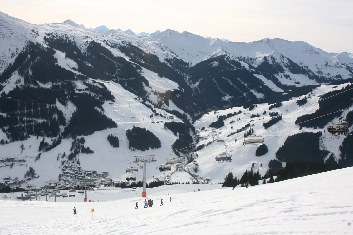 The village of Hinterglemm in snow, with chairlifts above the houses and snowy ridges behind