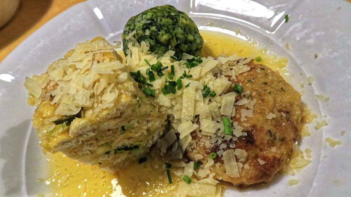 Kaspressknödel, a fried cheese dumpling and a layered dumpling in broth under grated cheese, with a green spinach dumpling