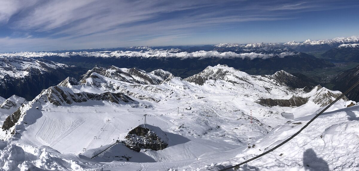 The Kitzsteinhorn ski area in snow seen from the summit, with a piste running down past the mountain station
