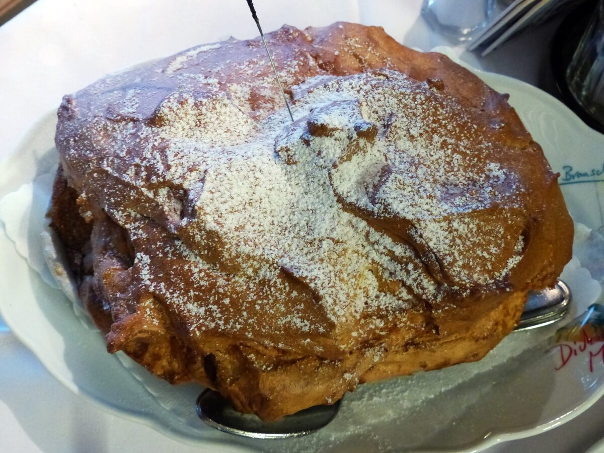 A golden Salzburger Nockerl soufflé dusted with icing sugar on a white plate