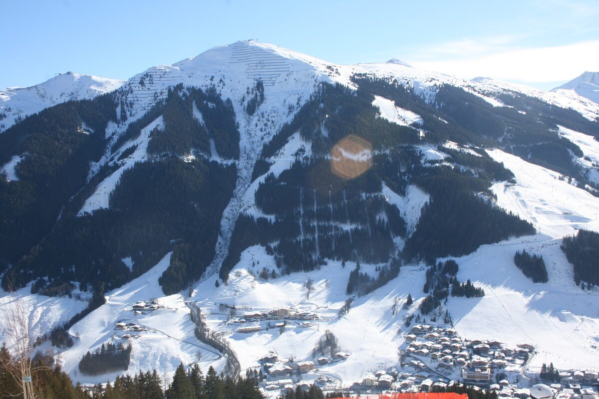Snowy slopes of Schattberg West across the valley from Hinterglemm, with the village below and skiers on the piste